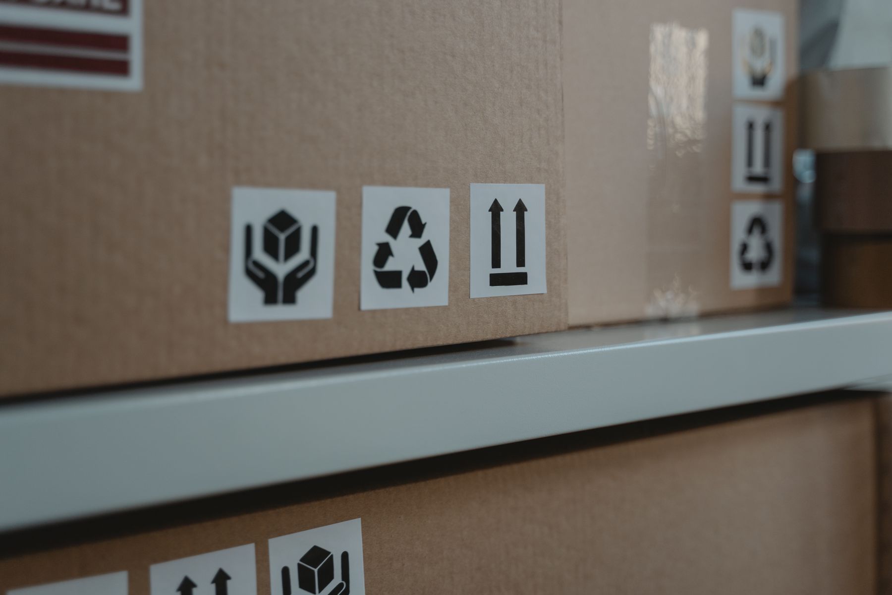 Cartons d'expédition portant les pictogrammes de recyclage, de fragilité et de sens de manutention.