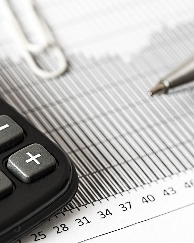 Calculatrice, stylo et tableau de chiffres imprimé, évoquant le calcul d'un devis.